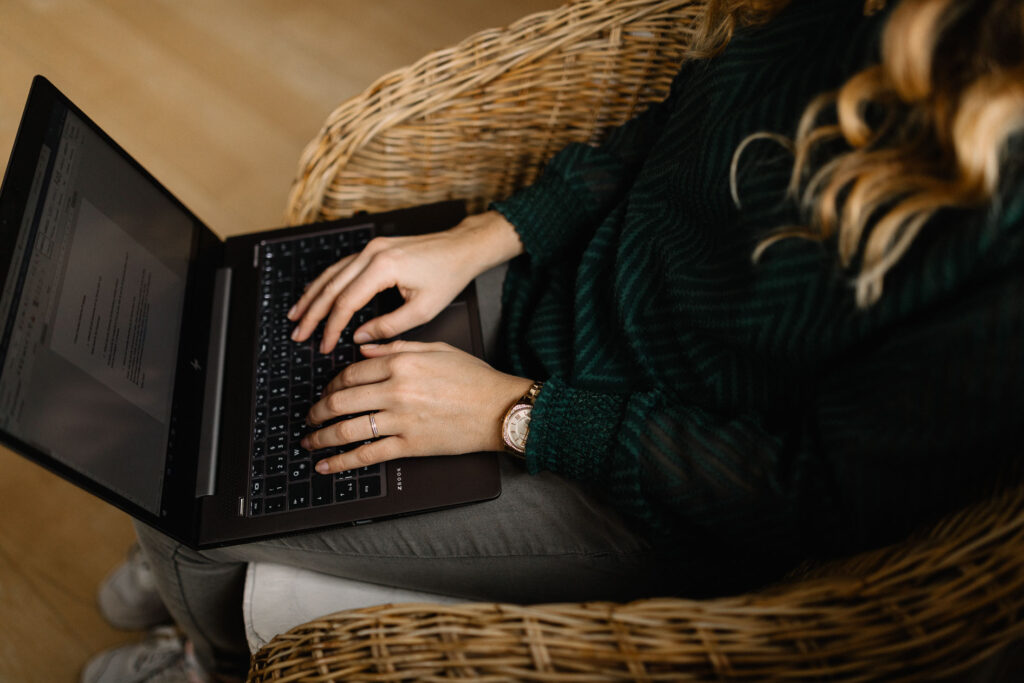 Texterin mit Laptop auf dem Schoß beim Blogartikel schreiben lassen